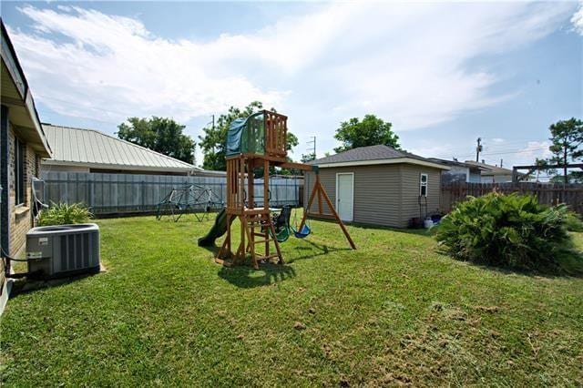 view of jungle gym featuring an outbuilding, a yard, central AC, and a fenced backyard