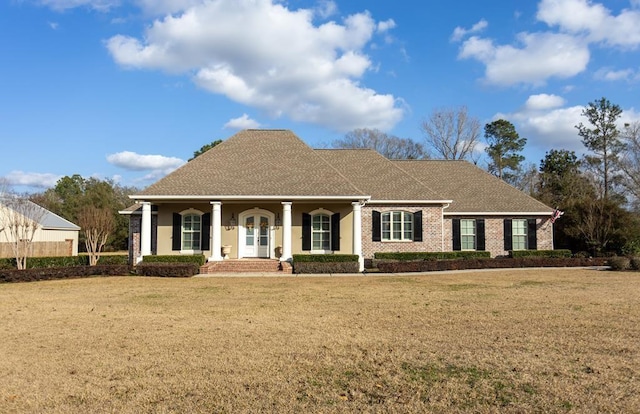 view of front of home featuring a front lawn, roof with shingles, a porch, and brick siding