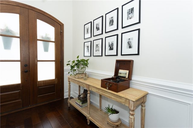 foyer entrance with french doors, a wainscoted wall, and dark wood-style flooring