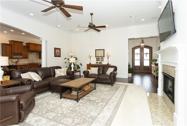 living room with a glass covered fireplace, ornamental molding, wood finished floors, french doors, and recessed lighting