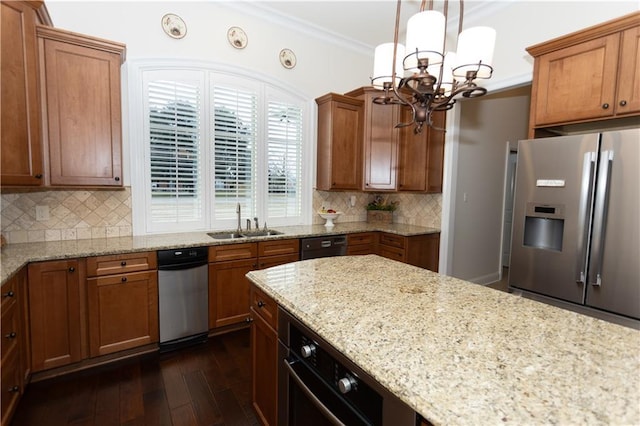 kitchen featuring a sink, hanging light fixtures, light stone counters, and stainless steel fridge