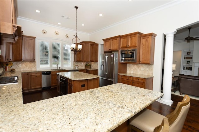 kitchen featuring stainless steel appliances, light stone counters, decorative columns, and decorative light fixtures