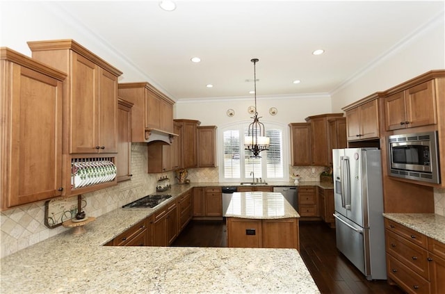 kitchen with light stone countertops, a kitchen island, appliances with stainless steel finishes, and decorative light fixtures