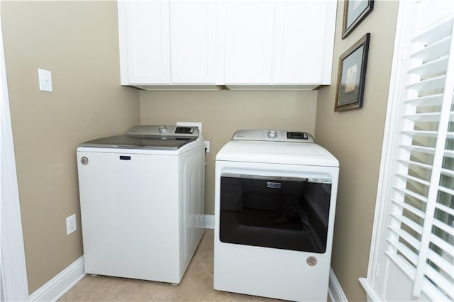 laundry room with cabinet space, light tile patterned floors, baseboards, and washing machine and clothes dryer