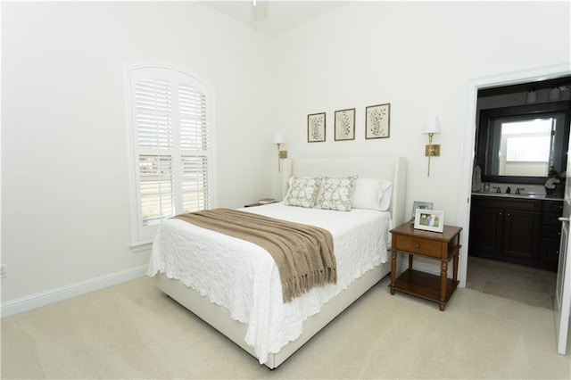 bedroom with light carpet, connected bathroom, and baseboards