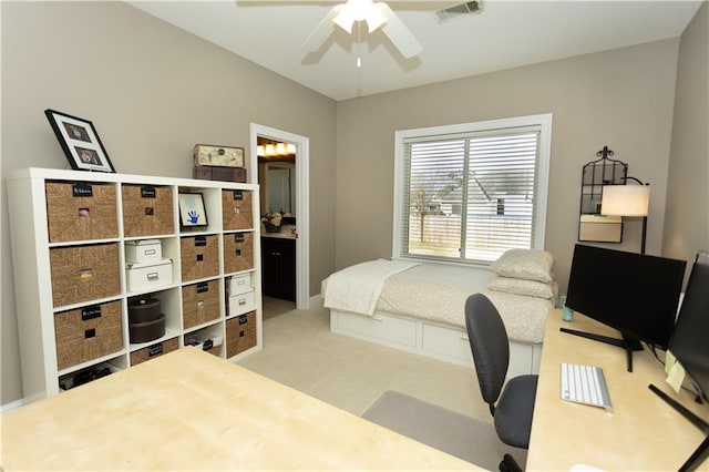 bedroom featuring light carpet, ensuite bathroom, visible vents, and a ceiling fan