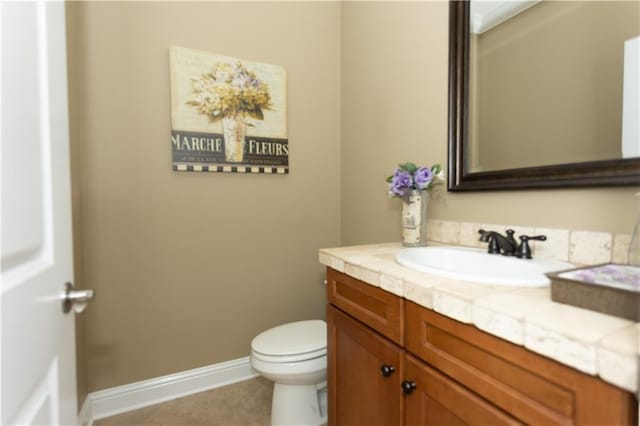 half bath with tile patterned flooring, toilet, vanity, and baseboards