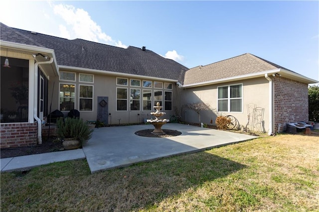 rear view of house with brick siding, a patio, a lawn, and stucco siding