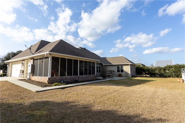 back of property with a yard, brick siding, an attached garage, and a sunroom