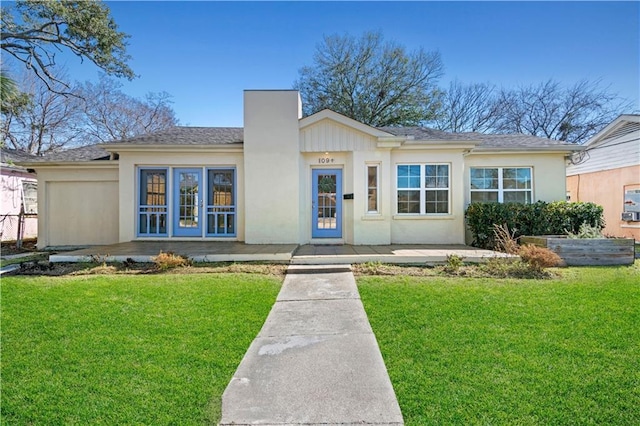 view of front of home featuring a chimney, a front yard, and stucco siding