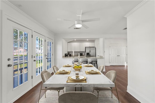 dining space with dark wood-style floors, crown molding, and baseboards