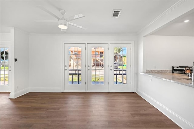 doorway with dark wood-style flooring, visible vents, crown molding, and baseboards