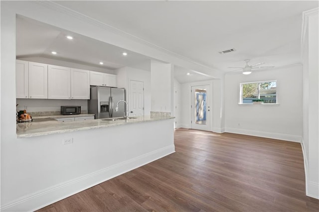 kitchen featuring black microwave, white cabinetry, baseboards, stainless steel fridge with ice dispenser, and light stone countertops