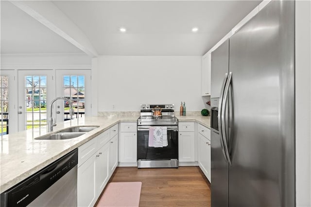 kitchen featuring white cabinets, dark wood-style floors, a peninsula, stainless steel appliances, and a sink