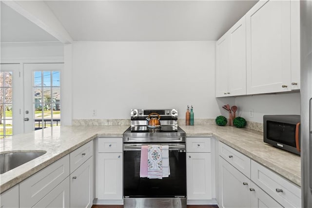 kitchen featuring a sink, light stone countertops, white cabinets, and stainless steel range with electric cooktop