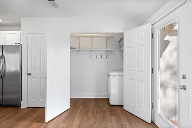 laundry area with light wood-type flooring, laundry area, visible vents, and baseboards