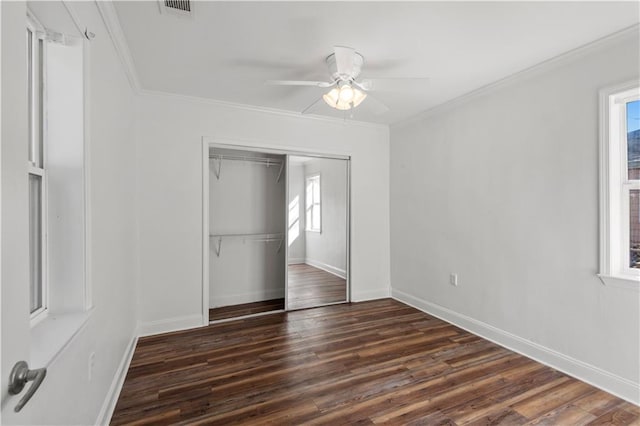unfurnished bedroom featuring a closet, visible vents, dark wood-style flooring, and ornamental molding