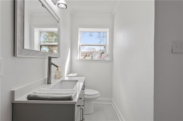 bathroom featuring toilet, ornamental molding, vanity, baseboards, and tile patterned floors
