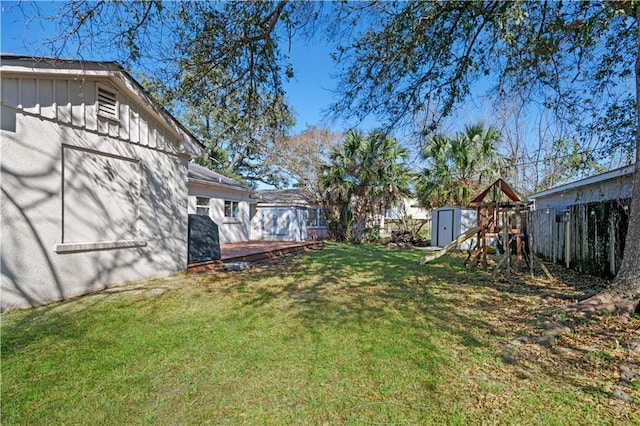 view of yard with fence private yard, a playground, an outdoor structure, and a storage shed