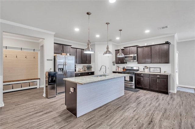 kitchen with a kitchen island with sink, a sink, dark brown cabinets, appliances with stainless steel finishes, and pendant lighting