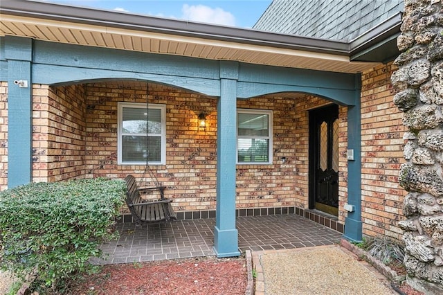 property entrance with a patio area and brick siding