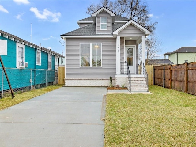 view of front facade with a front lawn, roof with shingles, cooling unit, and fence