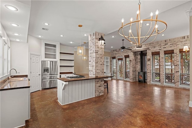 kitchen with pendant lighting, dark countertops, appliances with stainless steel finishes, open floor plan, and a sink