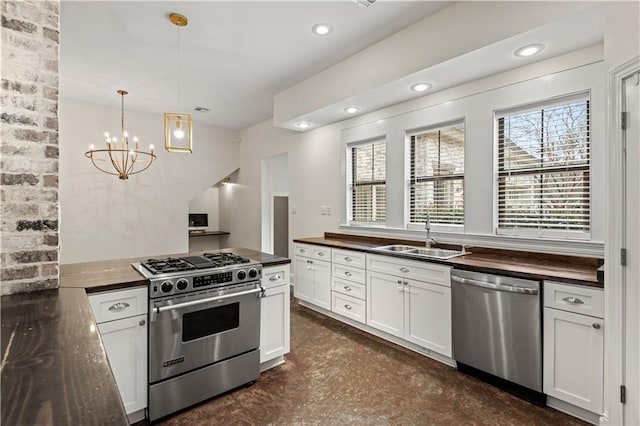 kitchen with dark countertops, appliances with stainless steel finishes, a sink, and decorative light fixtures