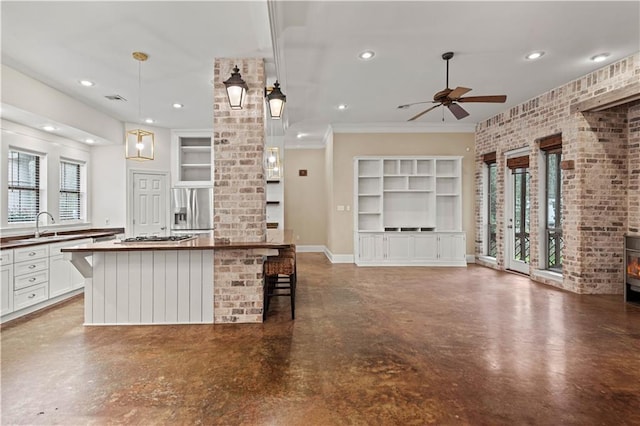 kitchen featuring built in features, a breakfast bar area, hanging light fixtures, open floor plan, and white cabinets