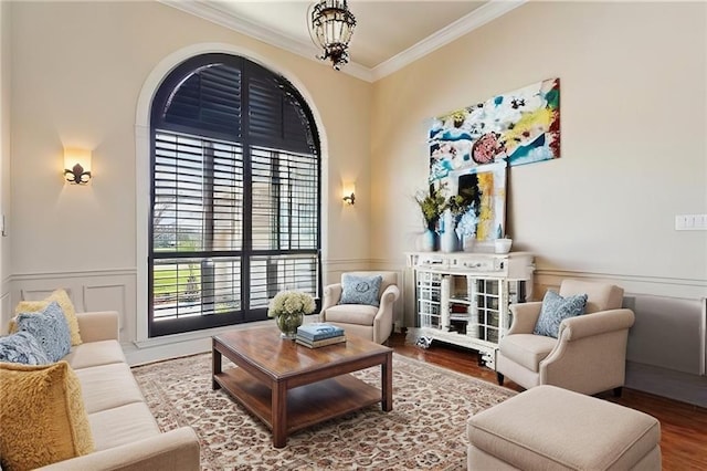 sitting room featuring wainscoting, wood finished floors, crown molding, a decorative wall, and a notable chandelier