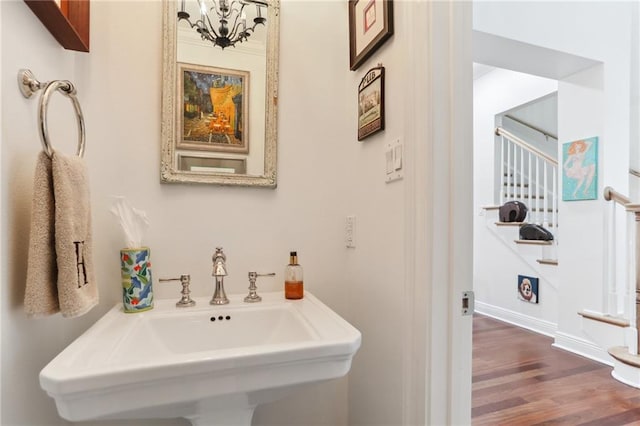 bathroom with an inviting chandelier, a sink, baseboards, and wood finished floors