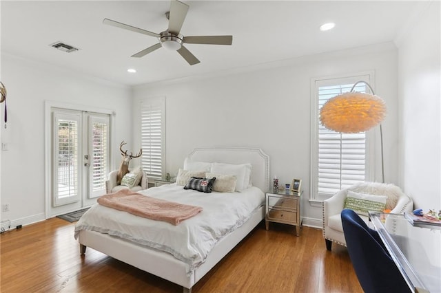 bedroom featuring crown molding, wood finished floors, visible vents, and access to exterior