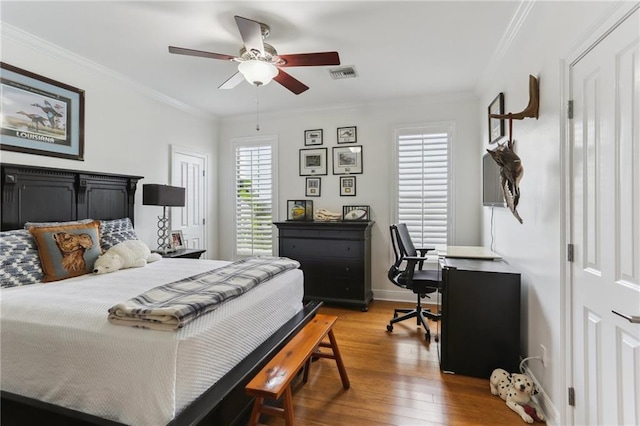 bedroom featuring baseboards, visible vents, ceiling fan, wood finished floors, and crown molding