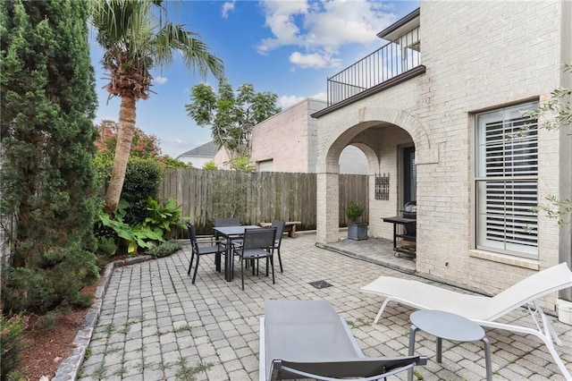 view of patio featuring a balcony, fence, and outdoor dining space