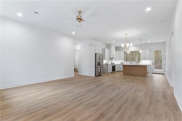 kitchen featuring pendant lighting, stainless steel appliances, open floor plan, white cabinetry, and a kitchen island