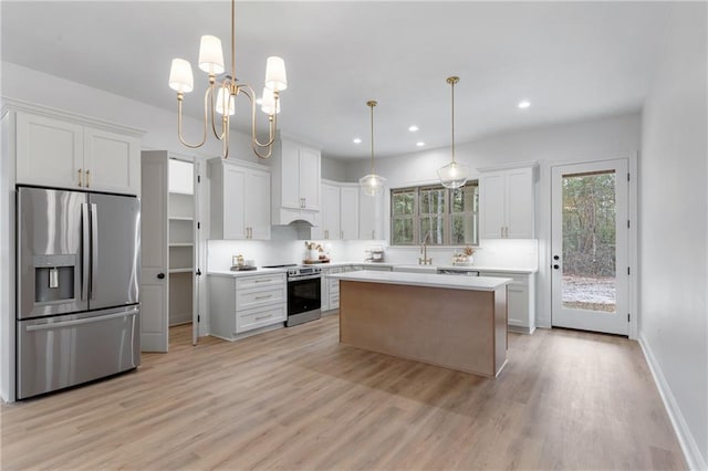 kitchen with stainless steel appliances, a kitchen island, white cabinetry, hanging light fixtures, and light countertops