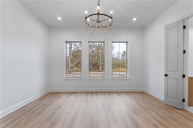 unfurnished dining area with baseboards, an inviting chandelier, and light wood-style floors