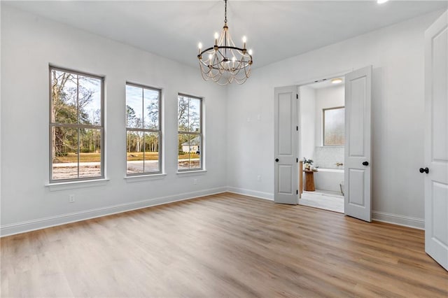 interior space with a notable chandelier, baseboards, and wood finished floors