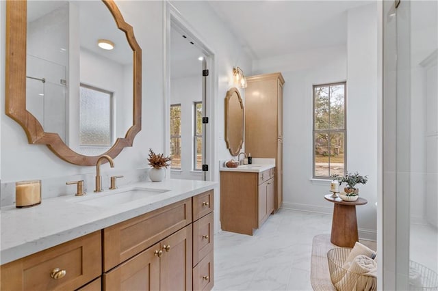 bathroom featuring marble finish floor, two vanities, a sink, and baseboards