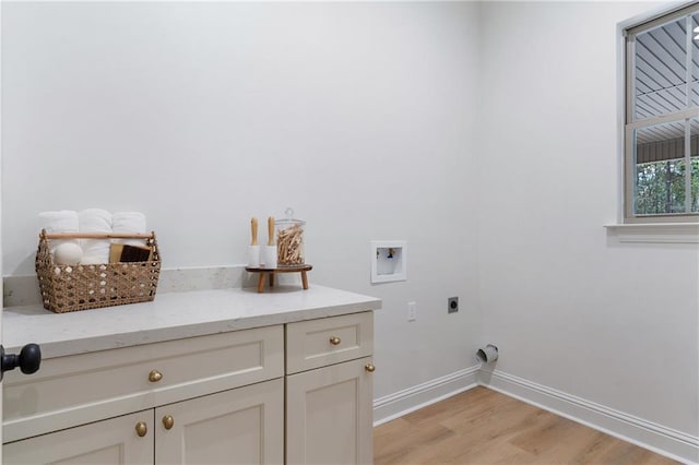 washroom featuring hookup for a washing machine, cabinet space, light wood-style flooring, hookup for an electric dryer, and baseboards