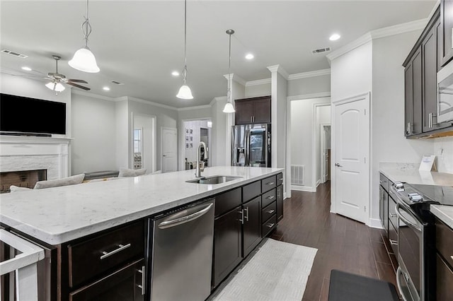 kitchen featuring decorative light fixtures, stainless steel appliances, visible vents, a kitchen island with sink, and a sink