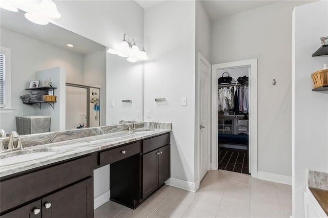 full bath with double vanity, a stall shower, a spacious closet, and a sink