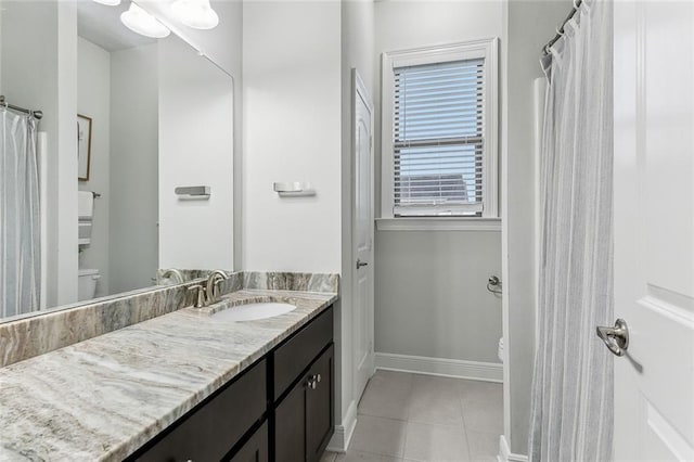 bathroom featuring baseboards, toilet, tile patterned floors, vanity, and a closet