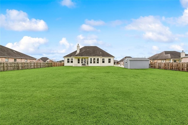 back of house featuring a lawn, a chimney, and a fenced backyard