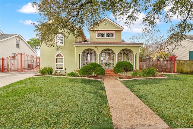 view of front facade with a tile roof, stucco siding, covered porch, a front yard, and fence