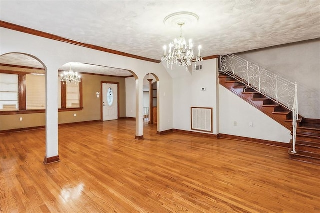 5116 Franklin Ave, New Orleans, LA 70122 - unfurnished living room featuring a chandelier, arched walkways, light wood finished floors, stairway, and crown molding