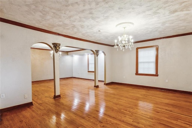 5116 Franklin Ave, New Orleans, LA 70122 - empty room featuring arched walkways, a chandelier, healthy amount of natural light, a textured ceiling, and ornamental molding