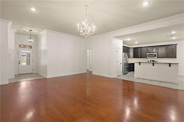 unfurnished living room with baseboards, ornamental molding, light wood-style flooring, and a notable chandelier