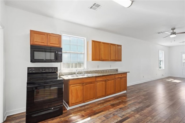 kitchen with visible vents, brown cabinetry, dark wood-style floors, black appliances, and a sink