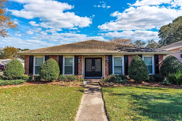 ranch-style house with brick siding, a front yard, and french doors